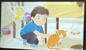 Na ilustracji widać chłopca w niebieskiej koszulce i ciemnych spodniach, który kuca na podłodze i głaszcze pomarańczowego kota w prążki. Kot wygląda na zadowolonego – ma przymknięte oczy i lekko uniesiony ogon.

Obok nich, po lewej stronie, unosi się mała wróżka w żółtej sukience w białe kropki, z jasnymi włosami i skrzydełkami otoczonymi błyszczącym pyłem. W tle widać miskę dla kota z rysunkiem łapki, a na podłodze rozlany napój i kawałek jedzenia, co sugeruje, że wcześniej wydarzył się mały bałagan.

Scena jest ciepła i przyjazna, utrzymana w pastelowych kolorach, przedstawiająca moment troski i przyjaźni między dzieckiem a zwierzęciem.