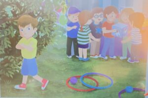 Na ilustracji widać grupę dzieci bawiących się na świeżym powietrzu. W tle, po prawej stronie, stoi kilka uśmiechniętych dzieci, które z zainteresowaniem oglądają przezroczyste pudełko – wygląda na to, że coś w nim losują lub oglądają zabawkę. Wokół nich panuje radosna atmosfera, a w tle widać balony i zieleń, co sugeruje, że to festyn lub piknik.

Na pierwszym planie, po lewej stronie, stoi chłopiec w żółtej koszulce, niebieskich spodenkach i czerwonych trampkach. Ma skrzyżowane ręce i niezadowoloną minę. Odwraca się od grupy, jakby był zły, zazdrosny lub urażony, że nie bierze udziału w zabawie.

Na trawie przed nim leżą kolorowe obręcze i piłki, co wskazuje, że wcześniej dzieci bawiły się w gry ruchowe. Scena pokazuje kontrast między radością grupy a samotnością chłopca, który czuje się pominięty.