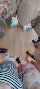 Na zdjęciu widać grupę dzieci stojących w kręgu na jasnej, drewnianej podłodze. Ujęcie wykonano z góry, więc widać głównie ich nogi i stopy. Każde dziecko ma na sobie kolorowe, nie do pary skarpetki – w paski, kropki, z motywami zwierząt i różnymi wzorami.

Ubrania dzieci są codzienne i wygodne – bluzy, koszulki i spodnie w jasnych kolorach, niektóre z nadrukami. Układ nóg tworzy zamknięty krąg, co nadaje zdjęciu wrażenie wspólnoty i radości.

Fotografia prawdopodobnie przedstawia moment obchodów Dnia Kolorowej Skarpetki, symbolizującego solidarność z osobami z zespołem Downa.