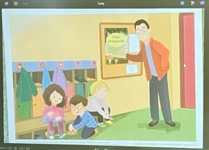 Na tym obrazku widzę ilustrację przedstawiającą scenę w przedszkolu lub szkole:

Postacie:

Nauczyciel/opiekun - mężczyzna w pomarańczowej kurtce i okularach, stojący po prawej stronie, trzymający tablet lub urządzenie mobilne
Troje dzieci siedzących na podłodze:
Dziewczynka w różowej bluzie z ciemnymi włosami
Chłopiec w niebieskiej koszuli
Dziewczynka w szarej bluzce z jasnymi włosami
Piesek siedzący obok dzieci
Otoczenie:

Żółta ściana z tablicą informacyjną zawierającą tekst "Uno proyecto" (lub podobny)
Wieszaki z kolorowymi kurkami (zielona, niebieska, fioletowa) z rysunkami dzieci nad nimi
Niebieska listwa pod wieszakami
Zielony dywan/mata na podłodze
Różowe drzwi po prawej stronie
Zielone elementy po lewej stronie